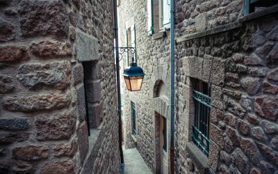 Narrow street with stone houses and vintage lamp in Mont Saint Michel village center