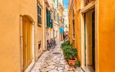 Kerkyra city narrow street view with yellow colorful houses and bikes during sunny day.