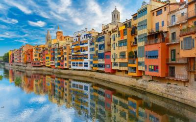 Colorful yellow and orange houses and famous house Casa Maso reflected in water river Onyar, in Girona, Catalonia, Spain.
