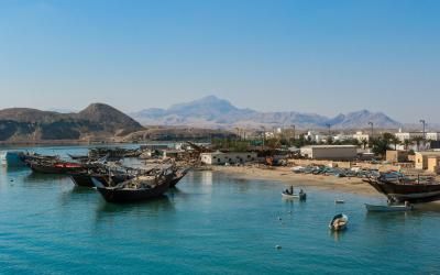 Coastal view of Sur Oman showcasing traditional dhows and tranquil waters under a clear blue sky