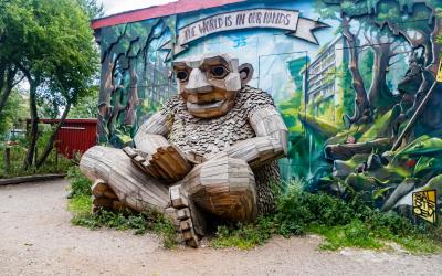 Wooden monkey sculpture in Freetown Christiania with the inscription The world is in our hands.